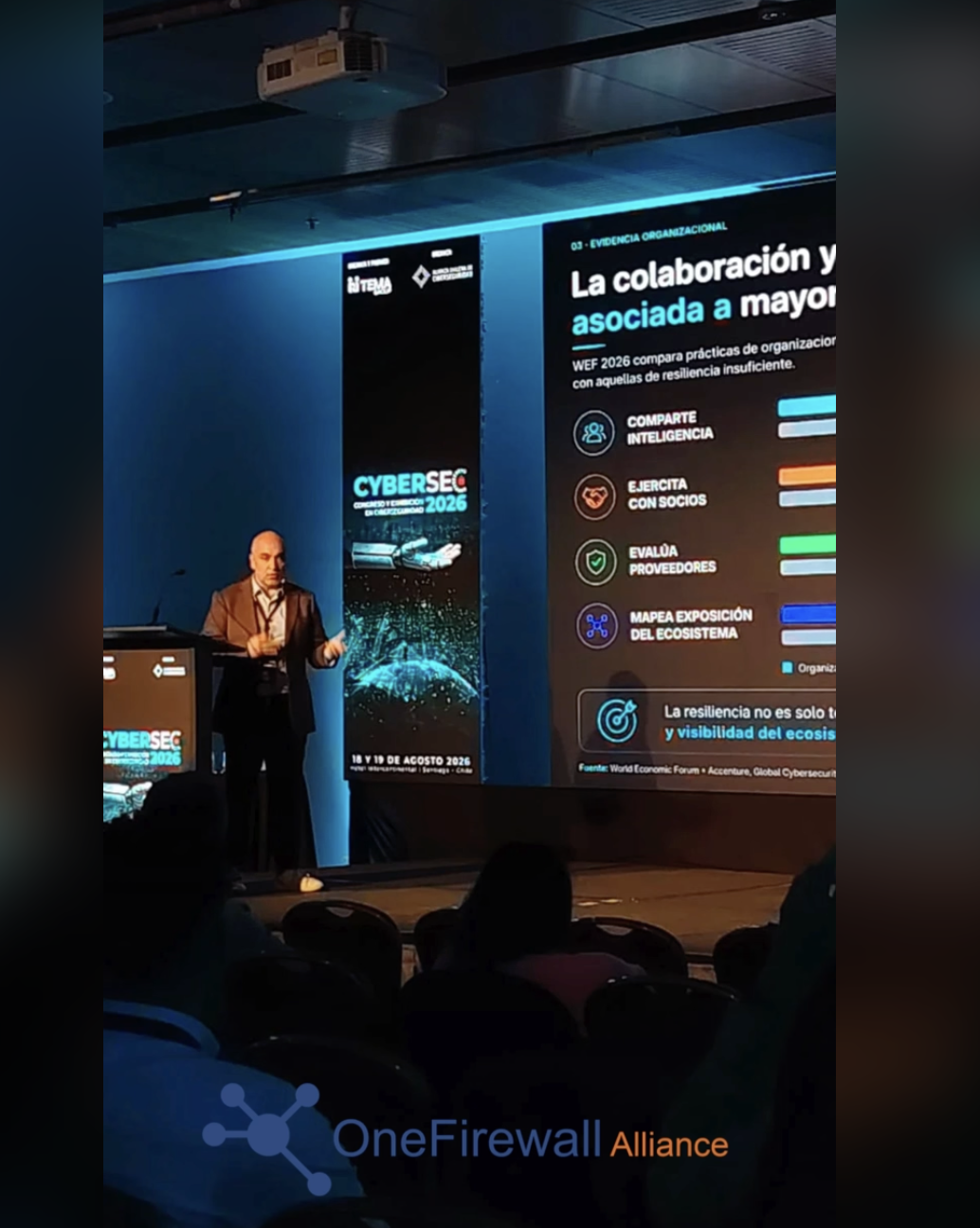 Speaker presenting on stage at CyberSec 2026 in front of a slide on collaboration and resilience
